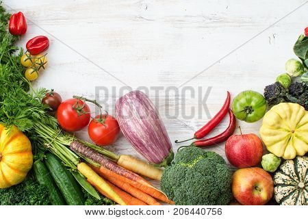 Above view of fresh raw vegetables, fruits and herbs on wooden white background, copy space for text, selective focus
