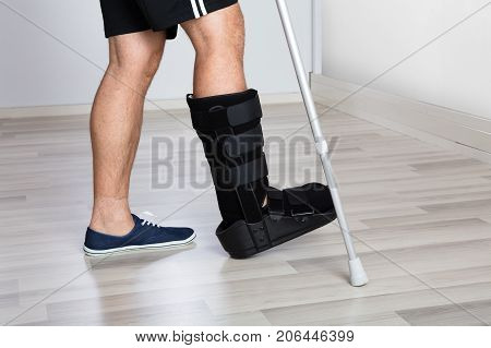 Low Section View Of A Injured Person's Leg With Crutches And Walking Brace