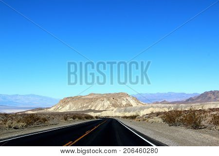 Road in the Death Valley National Park with blue sky background, California.