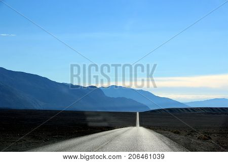 Road in the Death Valley National Park with colorful sky background, California.