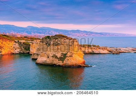 Beautiful sunset on Raouche, Pigeons' Rock. In Beirut, Lebanon.Sun and Stones are reflected in water.dense clouds in the sky.