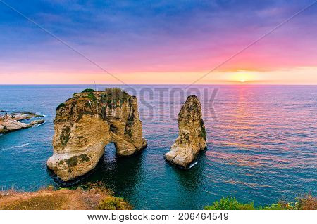 Beautiful sunset on Raouche, Pigeons' Rock. In Beirut, Lebanon.Sun and Stones are reflected in water.dense clouds in the sky.