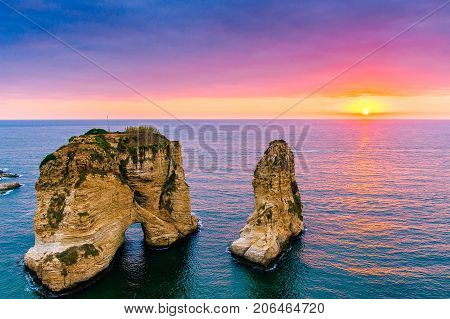Beautiful sunset on Raouche, Pigeons' Rock. In Beirut, Lebanon.Sun and Stones are reflected in water.dense clouds in the sky.