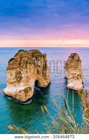 Beautiful sunset on Raouche, Pigeons' Rock. In Beirut, Lebanon.Sun and Stones are reflected in water.dense clouds in the sky.