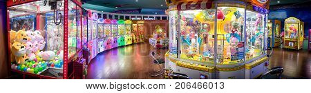 BANGKOK THAILAND - AUGUST 11: Various kinds of crane crabber arcade machines light and lined up in an arcade in Central shopping mall on August 11 2017 in Bangkok.