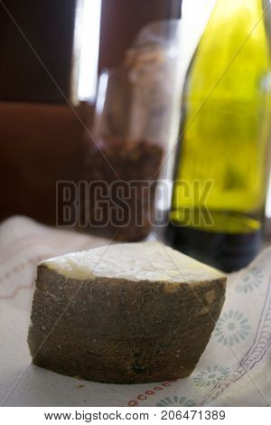 wedge of sardinian pecorinowith in background a bottle of red wine