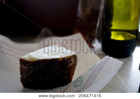 wedge of sardinian pecorinowith in background a bottle of red wine