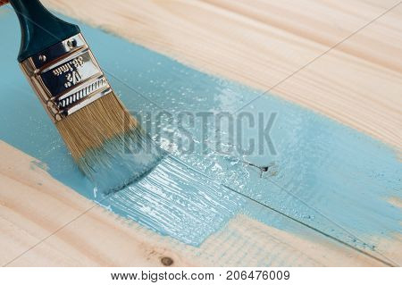worker paints board. the employee paints the a wooden table. worker paints wooden board. blue paint