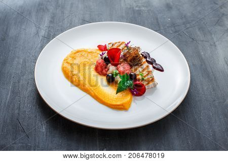 Grilled turkey fillet with pumpkin puree and vegetables on white plate. Close view