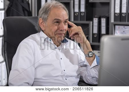 Smiling senior man with white shirt sitting at a desk