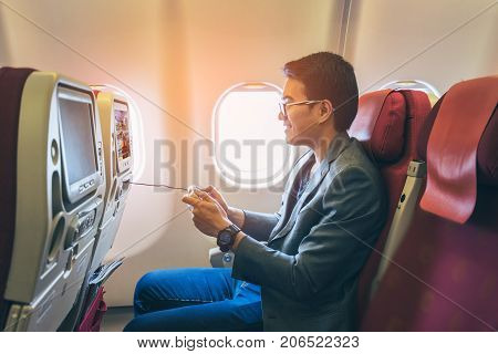 Young asian business man smiling and playing game with happinest in airplane