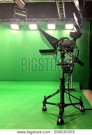 Modern empty green video recording and broadcasting studio with tv channel led screen and metalic stands, text prompter, lights on