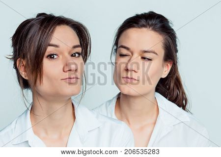 Studio portrait of young female twins sisters on gray