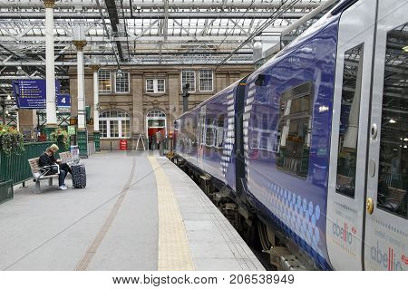 Edinburgh, UK: May 26, 2016: Two people sit waiting for their train at Waverley Railway Station. Waverley is the main railway station in Edinburgh.