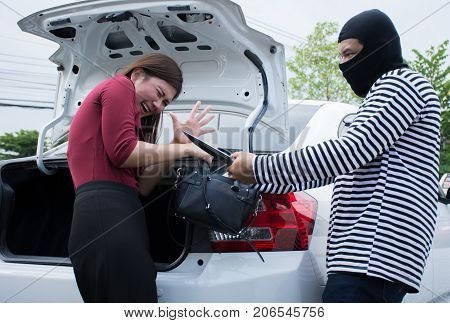 Male robber robbing a handbag threatening with knife to scared Asian woman,criminal concept