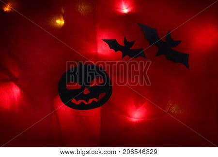Pumpkin and bats on a red background with lights. Halloween.