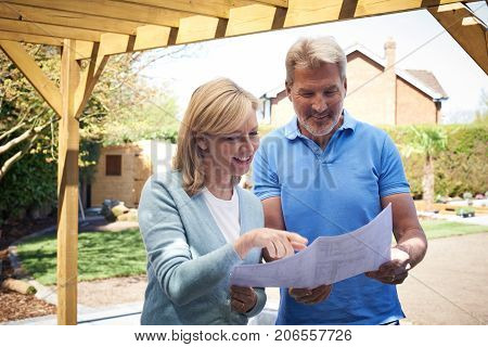 Mature Woman Looking At Design Plan With Landscape Gardener