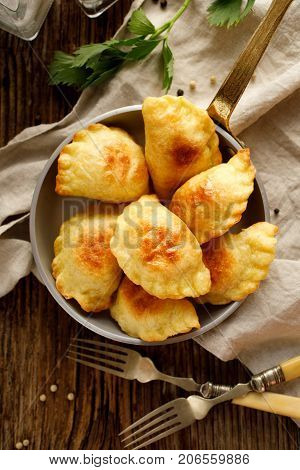 Baked dumplings stuffed with curd cheese and potatoes in a pan on wooden rustic table, nutritious and delicious vegetarian food,  Traditional Polish dish, top view