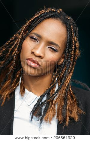 Confident young African American female. Pretty black woman in selective focus, contemptuous expression, girl on dark background, disdain concept