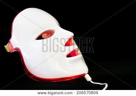 Light rejuvenating mask for facial skin therapy on black background