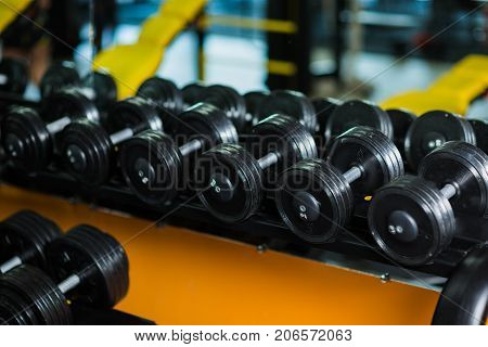 A full set of dumbbells, equipment for increasing strengh and muscle size, weight heavy sports routine, workouts, gyms on a dark blurred background.