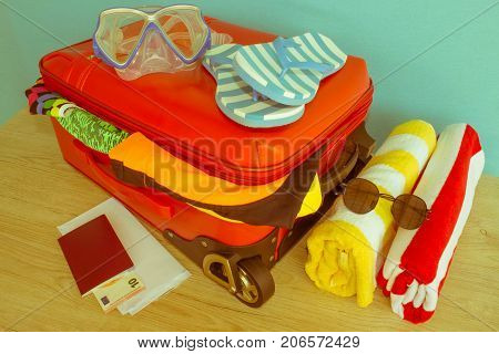 Anticipation of voyage. Women's clothes and accessories in red suitcase things prepared for travel - Retro color