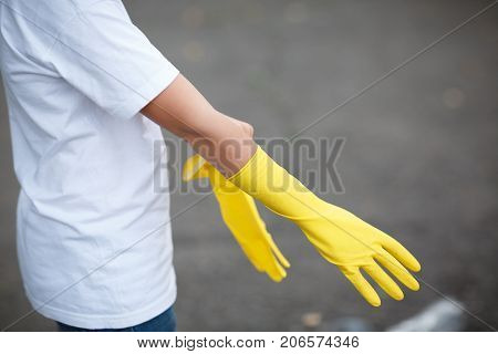 Outdoors cleaning. Environmental protection. Closeup cropped portrait. Getting started cleaning. Yellow rubber cleaning gloves closeup. Workhouse concept. Homework, washing and cleaning of the theme.
