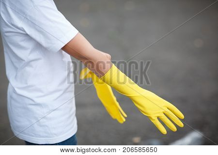 Outdoors cleaning. Environmental protection. Closeup cropped portrait. Getting started cleaning. Yellow rubber cleaning gloves closeup. Workhouse concept. Homework, washing and cleaning of the theme.