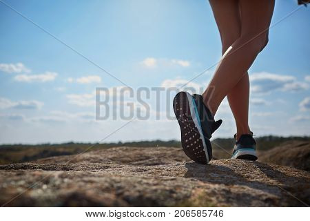 Sport legs. Woman hiker climbing rock on mountain peak cliff, her man giving hand and helping to climb. Assistance. Concept of sport and active life. Help, support, assistance in a dangerous situation