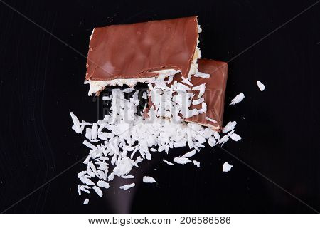 Homemade chocolate coconut bars with coconut flakes on top.