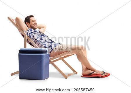 Tourist relaxing in a deck chair next to a cooling box isolated on white background