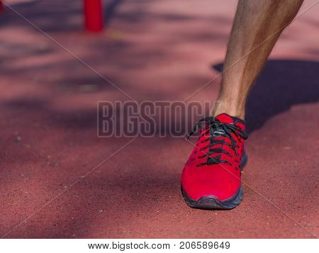 A strong man with sexy body is doing exercises on his feet. A handsome young man lifts weights with his feet in the park.