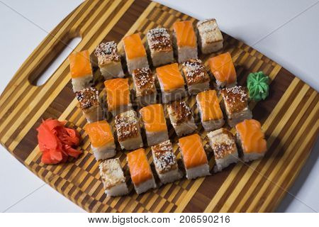 The set of rolls with ginger and wasabi on bamboo board. Unagi rolls and philadelphia rolls. View from above.