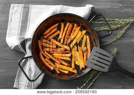 Frying pan with sweet potato fries on table