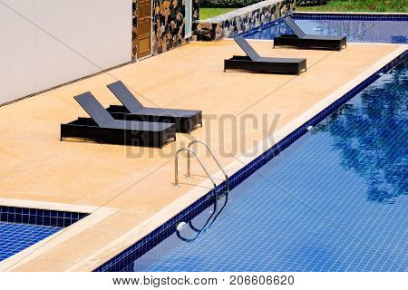 Black wicker daybed beside the swimming pool.