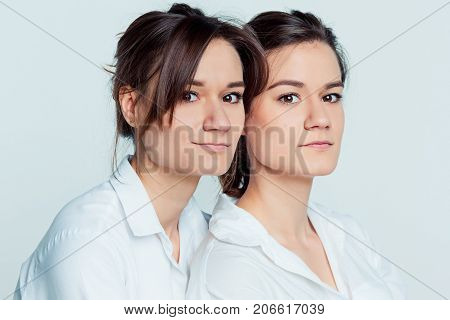 Studio portrait of young female twins sisters on gray