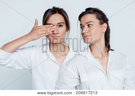 Studio portrait of young female twins sisters on gray