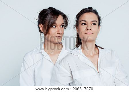 Studio portrait of young female twins sisters on gray