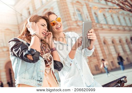 Smiling young friends using digital tablet. Beautiful woman with digital tablet in hands and headphones. Smiling face.