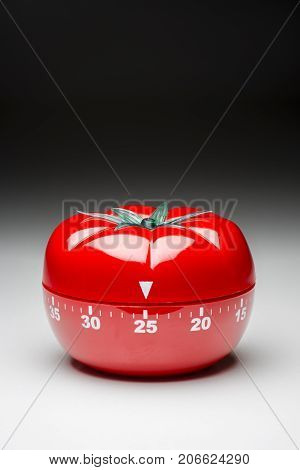 Tomato-shaped kitchen timer set at 25 minutes to fight procrastination in studying and working.