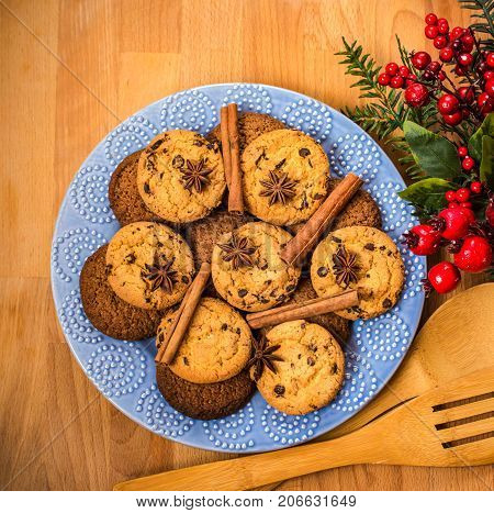 Christmas cookies with festive decoration. Plate with tasty New Year homemade sweets on wooden table. Gingerbread and christmas cookies with festive decor on wooden background.