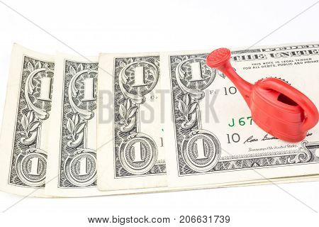 One Red Watering Can Laying On Four One Dollar Banknotes