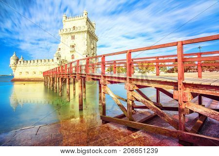 The iconic and spectacular Belem Tower and wooden jetty reflecting on Tagus River with low tides. Torre de Belem is Unesco Heritage and famous city landmark in Lisbon, Belem District, Portugal.