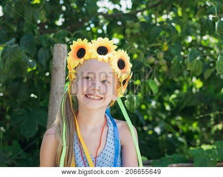 Portrait of beautiful girl with flowers of sunflowers on his head. The concept of a happy carefree childhood.