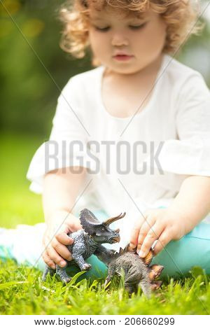 Toddler Kid Playing With A Toy Dinosaur