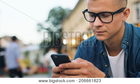 Close Up Shot Of Attractive Man In The Stylish Glasses Using Cell Phone For Chatting With Friends In