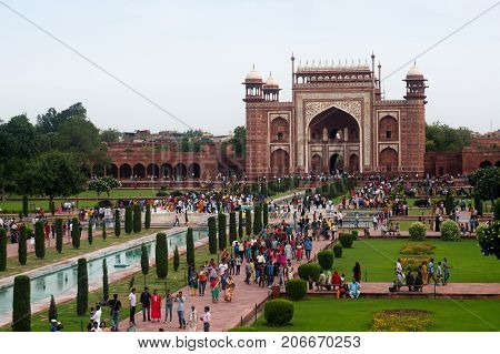 Agra, India - 12 Aug 2017: The huge arched sandstone entry gate for the Taj Mahal. This famous monument attracts huge crowds clearly seen here.