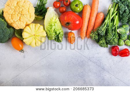 Above view of different colored rainbow vegetables on the light grey background, copy space for text below, selective focus