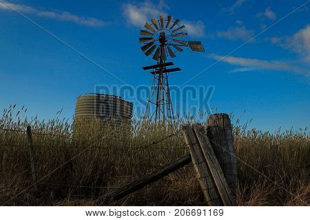 Old fenceline, broken tank and windmill in rural Australia