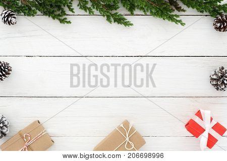Christmas background. Christmas frame made of fir leaves pine cones and present gifts box with decoration rustic elements on white wooden. Creative flat lay top view design
